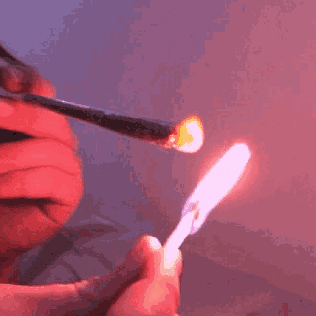 a person is holding a lighter with a pink flame on it