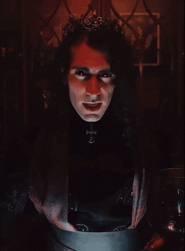 a man with red eyes and a crown on his head looks at the camera