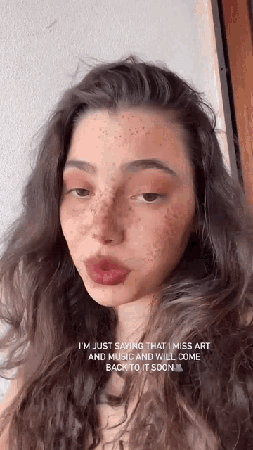 a woman with freckles on her face is saying that she miss art and music and will come back to it soon