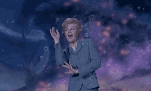 a woman in a suit is dancing in the water with bubbles around her .