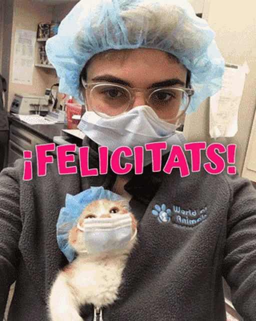 a woman wearing a surgical mask and goggles holds a cat in her arms with the words felicitats written above her