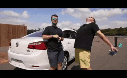 two men standing in front of a white volkswagen