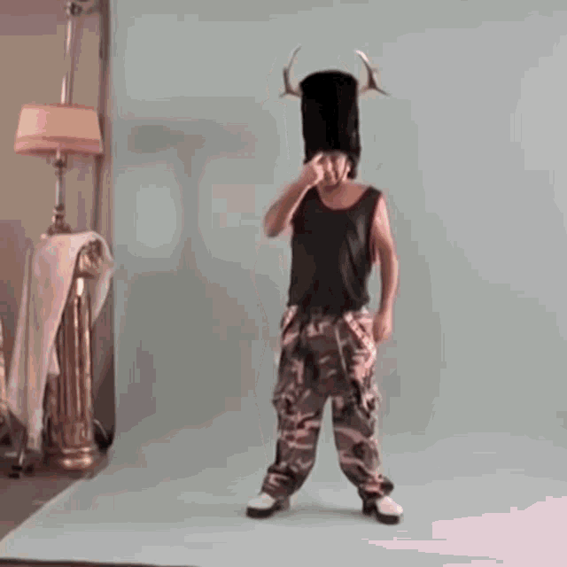 a man wearing a black tank top and pink pants is standing in front of a lamp