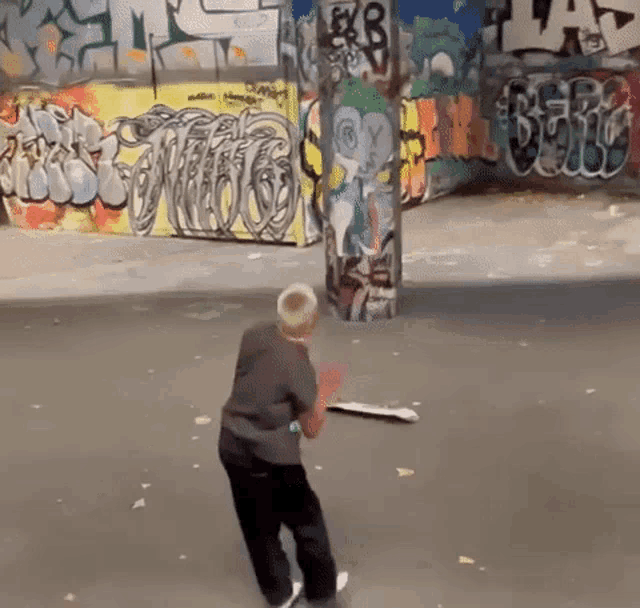 a boy is playing with a skateboard in front of a wall with graffiti on it including the letters eyb