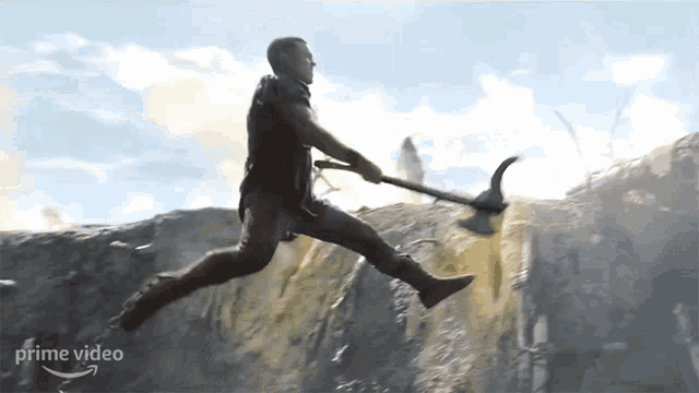 a man is jumping in the air while holding a large axe in front of a waterfall ..