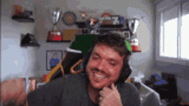 a man wearing headphones is smiling in front of a window .
