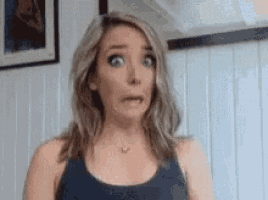 a woman is making a surprised face while standing in front of a window .