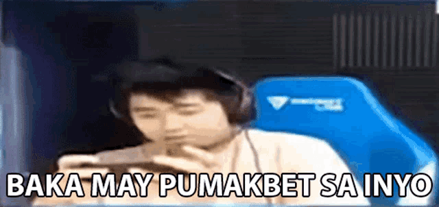 a man wearing headphones is sitting in a blue chair and playing a game