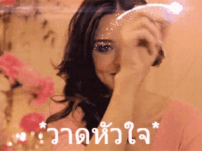 a woman in a pink shirt is covering her face with her hand in front of a pink background .