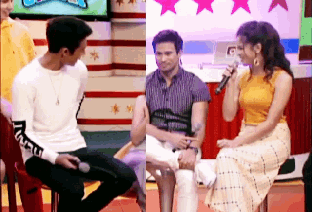 a man sitting next to a woman holding a microphone with the letter t on his shirt