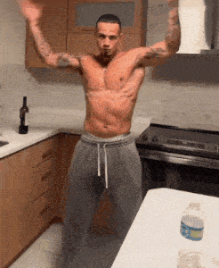 a shirtless man is dancing in a kitchen next to a bottle of water