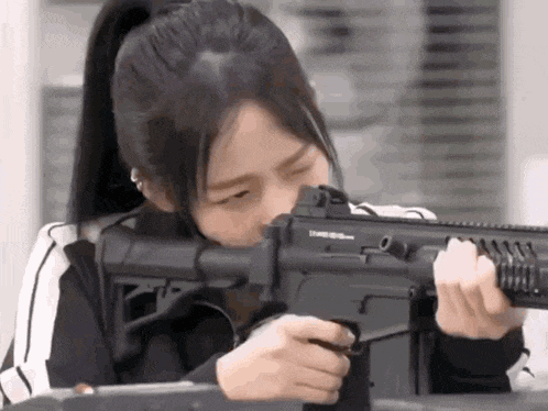 a young woman is holding a gun in her hand and looking at it .