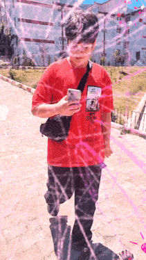 a boy wearing a red shirt that says ' o'neill ' on it is looking at his phone