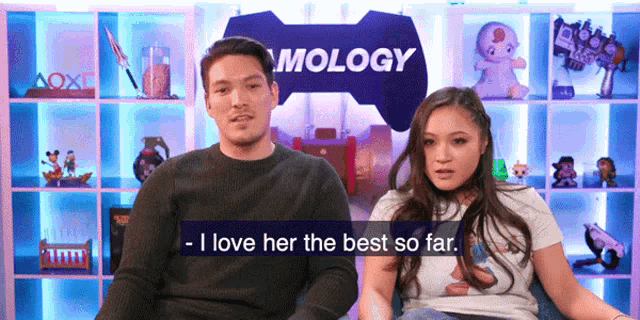 a man and a woman are sitting in front of a sign that says " mology "