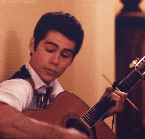 a man in a suit and tie is playing a guitar