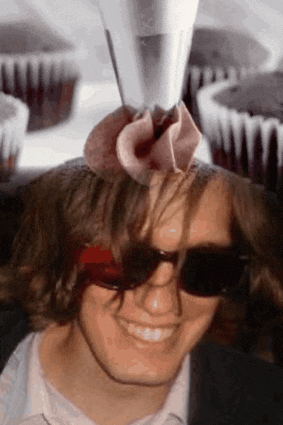 a man wearing sunglasses has a pink flower on his head