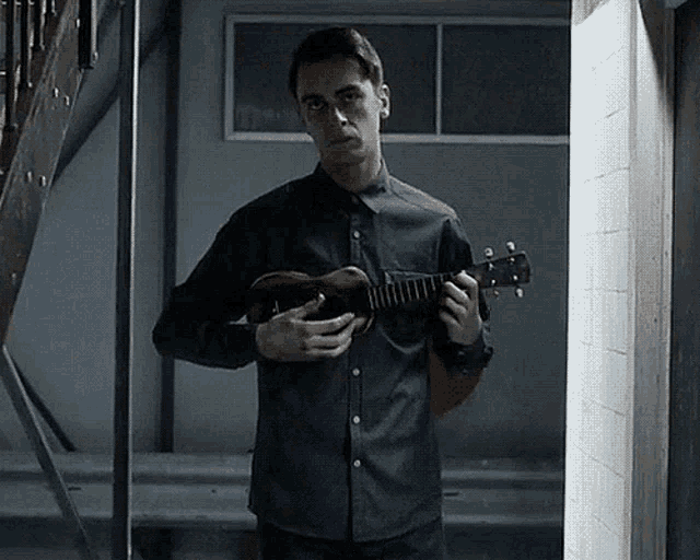 a man in a black shirt is holding a guitar in front of a mirror .