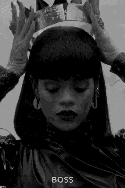 a black and white photo of a woman holding a crown on her head .