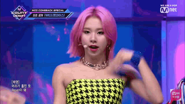 a woman with pink hair is standing in front of a microphone on stage .