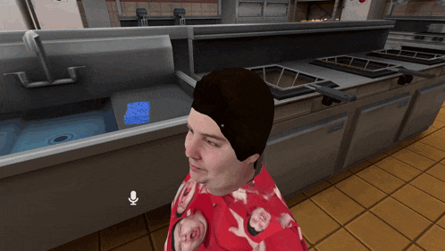 a man wearing a red shirt with pig faces on it stands in a kitchen