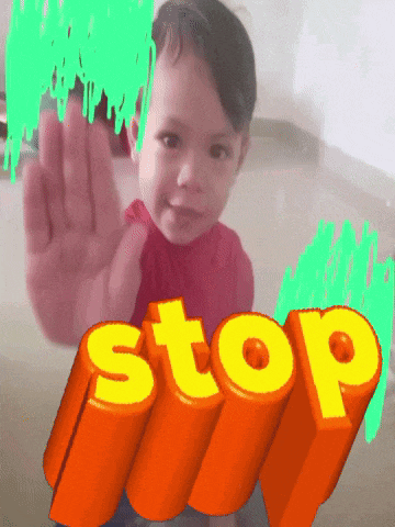 a child making a stop sign with a green background behind him