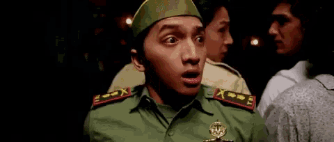 a man in a military uniform is making a funny face while standing in a crowd of people .