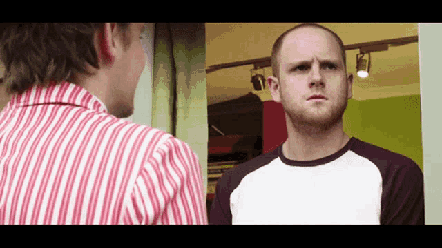 a man in a red and white striped shirt is looking at another man