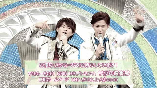 two men singing into microphones in front of a sign that says 150-8001 nhk bs premium
