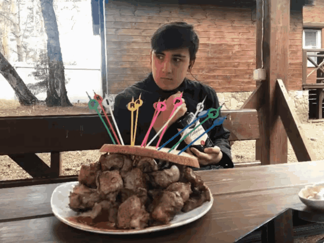 a man is sitting at a table with a plate of food and a bunch of toothpicks on it