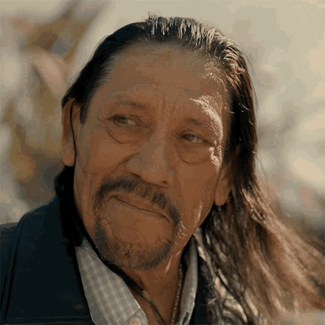 a man with long hair and a beard looks to the side