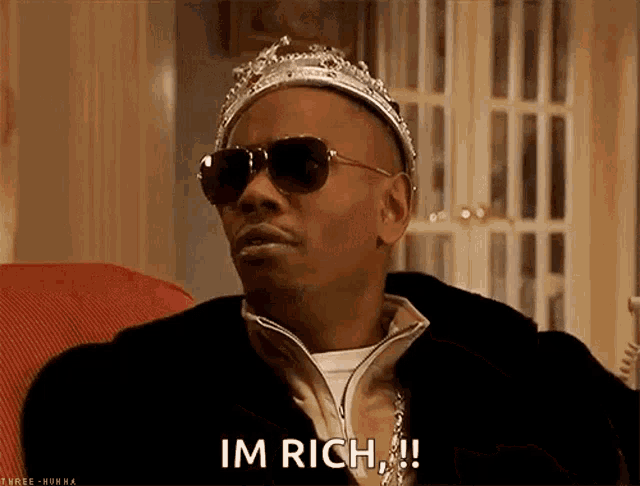 a man wearing a crown and sunglasses is sitting on a couch and saying im rich .