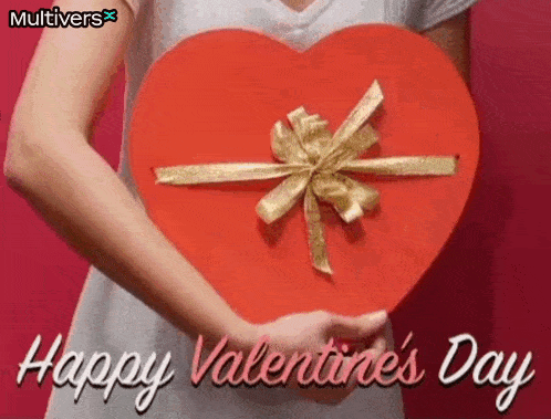a woman is holding a red heart shaped box with a gold ribbon on it .