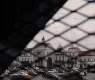 a view of a parking lot through a fence with a building in the background that says ' a ' on it