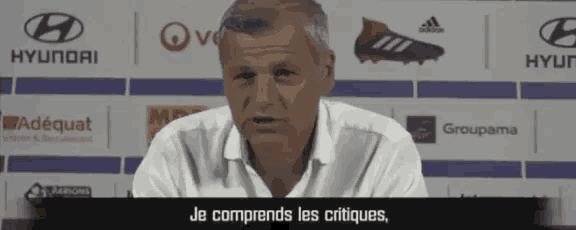 a man is giving a speech in front of hyundai adéquat groupama and adidas logos