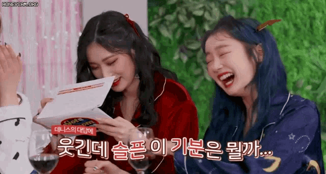 two girls are laughing while holding wine glasses