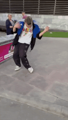 a man in a white shirt and blue jacket is dancing on the street