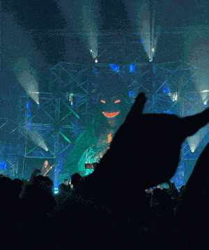 a crowd of people at a concert with a giant monster in the background