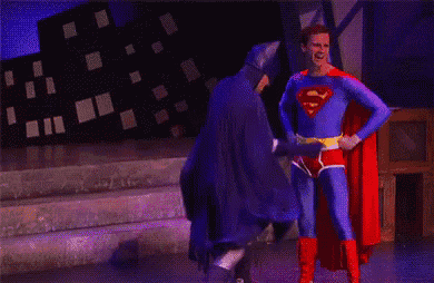 a man in a superman costume is standing next to batman