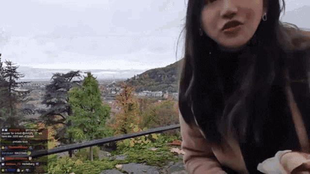 a woman is standing on a balcony with a view of a city in the background