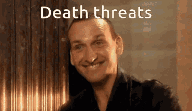 a man is smiling with the words death threats written below him