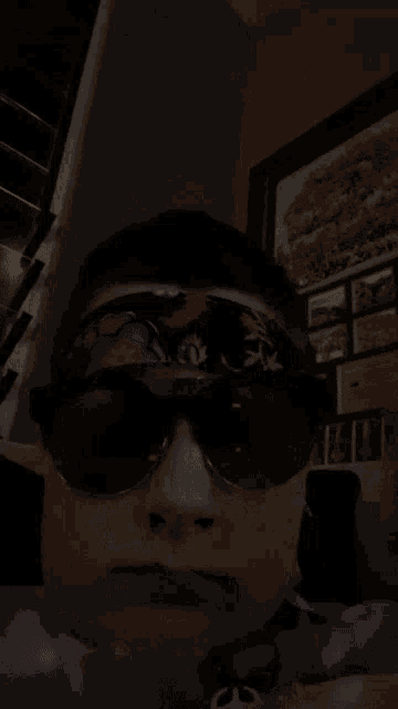 a person wearing sunglasses and a headband with a picture on the wall behind him