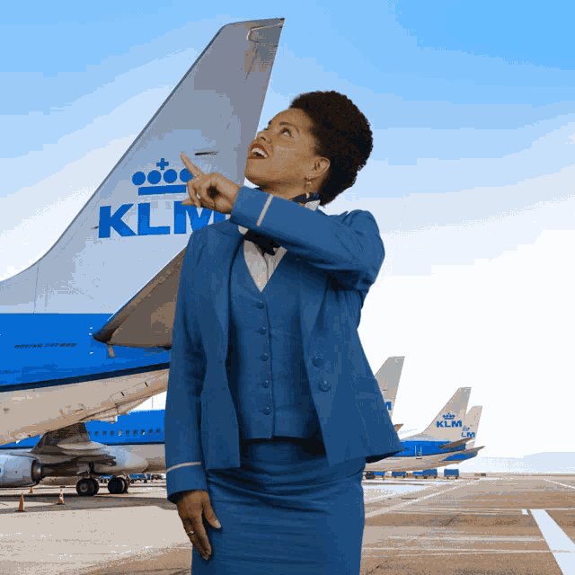 a stewardess pointing at a klm plane