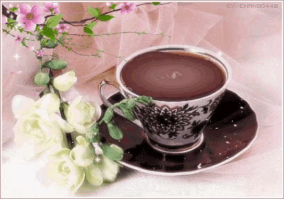 a cup of coffee sits on a saucer next to a vase of flowers