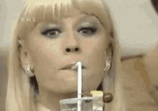 a close up of a woman drinking from a straw with her tongue out .