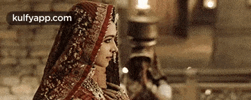 a woman in a veil is standing in front of a brick wall in a dark room .