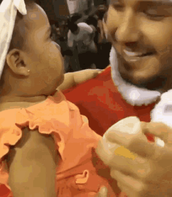 a man is holding a baby in his arms and the baby is looking at the man