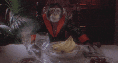 a monkey is sitting at a table with a bowl of bananas