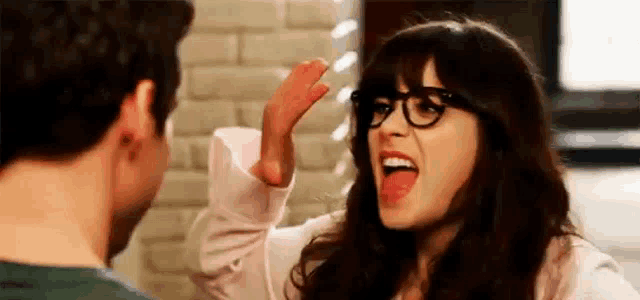 a woman is sticking her tongue out at a man while wearing glasses .