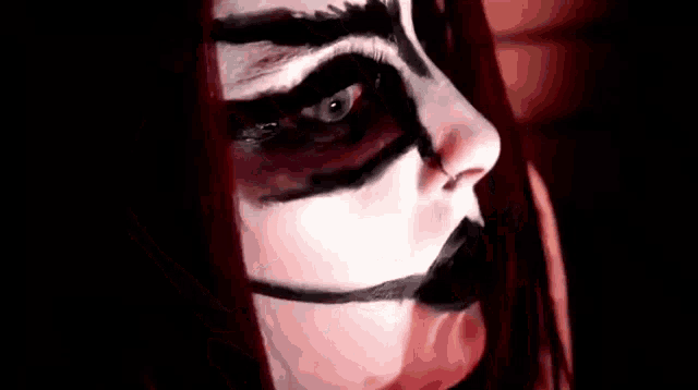 a close up of a woman 's face with black and red makeup and big eyes .