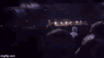 a group of people are dancing in a dark room with blue lights behind them .